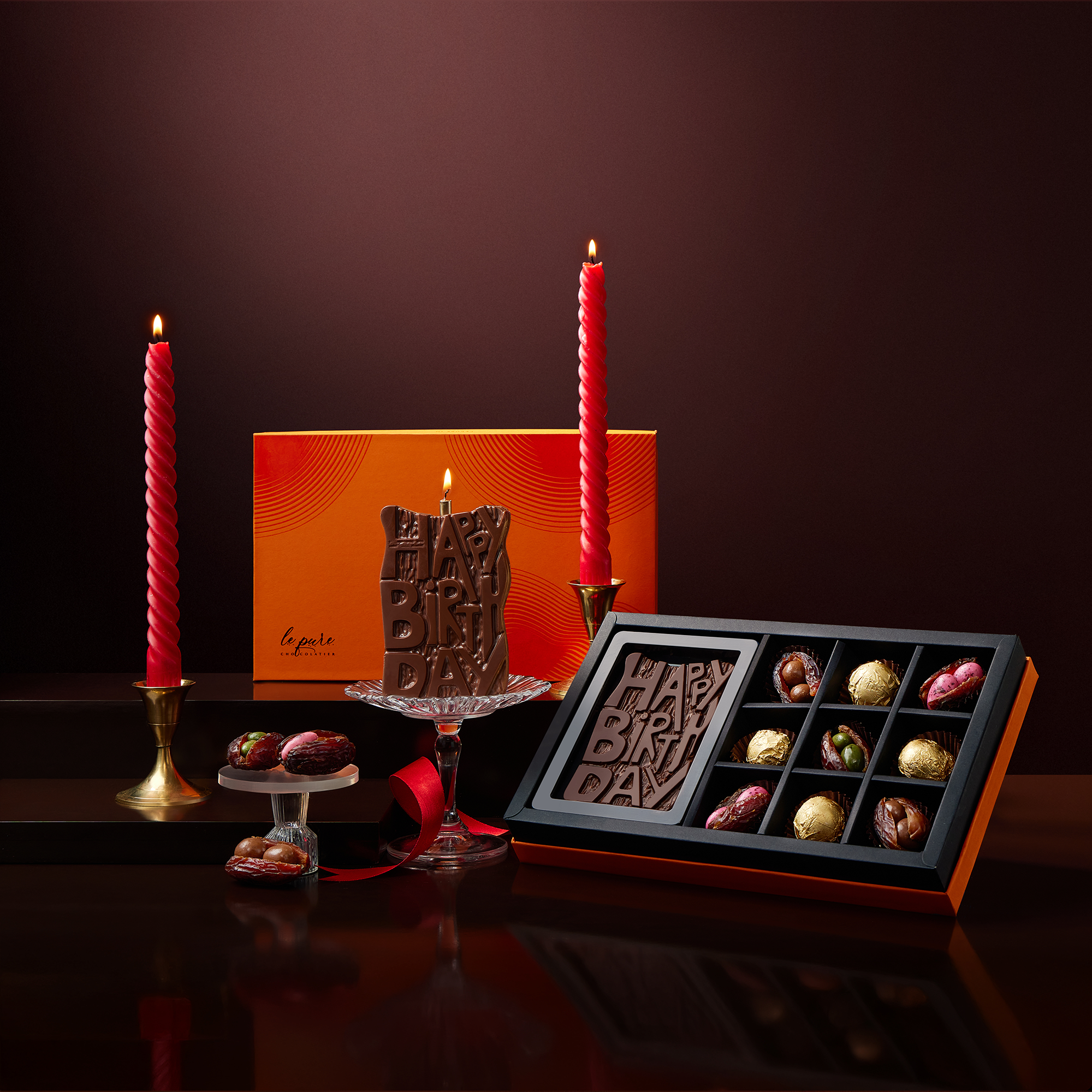 Birthday-themed chocolate set with candles and a cake on a dark background